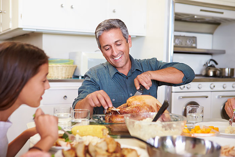 dad carving roast chicken at table